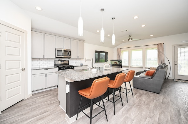 kitchen featuring stainless steel appliances, plenty of natural light, an island with sink, and pendant lighting