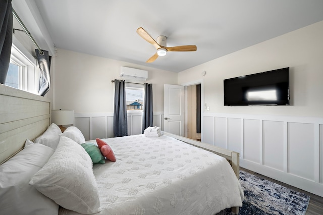 bedroom with hardwood / wood-style flooring, ceiling fan, and a wall mounted air conditioner