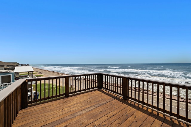 wooden deck featuring a water view and a view of the beach