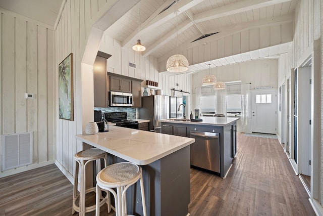 kitchen with kitchen peninsula, appliances with stainless steel finishes, high vaulted ceiling, pendant lighting, and dark hardwood / wood-style flooring