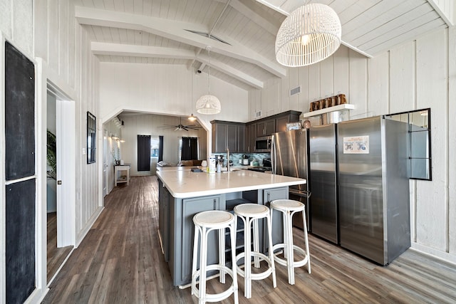 kitchen with dark brown cabinetry, a breakfast bar, dark hardwood / wood-style floors, decorative light fixtures, and a kitchen island with sink