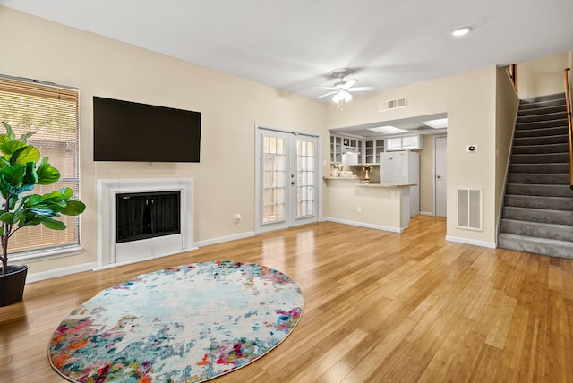 living room with french doors, light hardwood / wood-style flooring, a healthy amount of sunlight, and ceiling fan