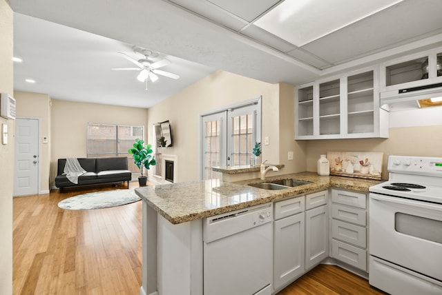 kitchen with white appliances, sink, light wood-type flooring, and kitchen peninsula