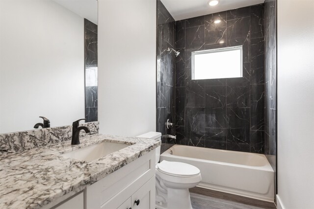 full bathroom featuring toilet, vanity, wood-type flooring, and tiled shower / bath