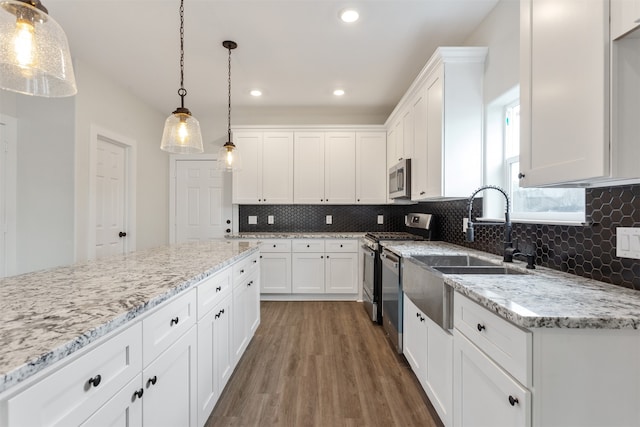 kitchen featuring appliances with stainless steel finishes, tasteful backsplash, dark hardwood / wood-style floors, white cabinets, and pendant lighting