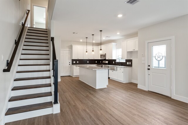 kitchen with hanging light fixtures, white cabinets, stainless steel appliances, and a center island