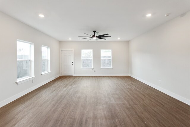 empty room featuring wood-type flooring, a healthy amount of sunlight, and ceiling fan