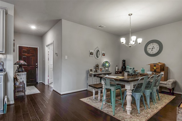 dining space with dark wood-type flooring and an inviting chandelier