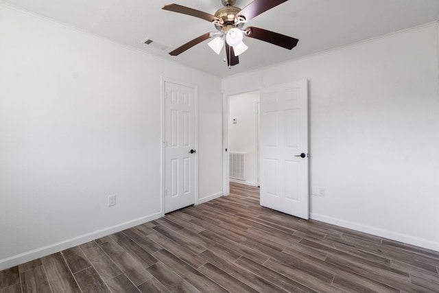 unfurnished bedroom featuring dark hardwood / wood-style flooring, ceiling fan, and crown molding