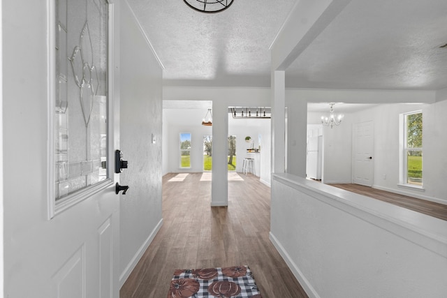 hallway featuring wood-type flooring, a textured ceiling, and a chandelier