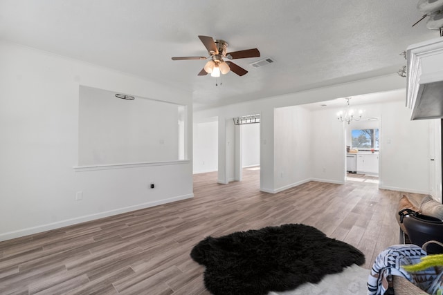 unfurnished living room featuring a textured ceiling, ceiling fan with notable chandelier, and light hardwood / wood-style flooring