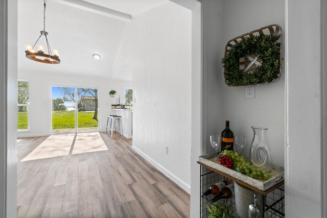 foyer entrance featuring a chandelier, lofted ceiling with beams, and wood-type flooring