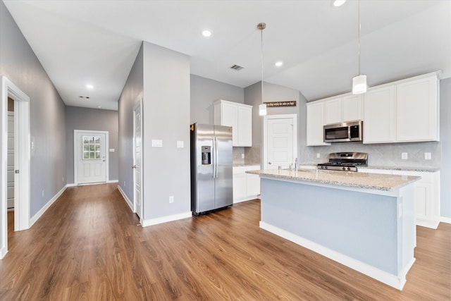 kitchen with white cabinetry, appliances with stainless steel finishes, decorative light fixtures, a kitchen island with sink, and light wood-type flooring