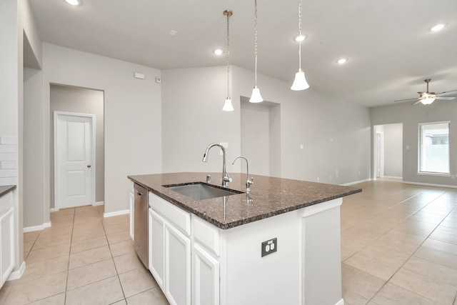 kitchen with dark stone counters, pendant lighting, sink, an island with sink, and white cabinets