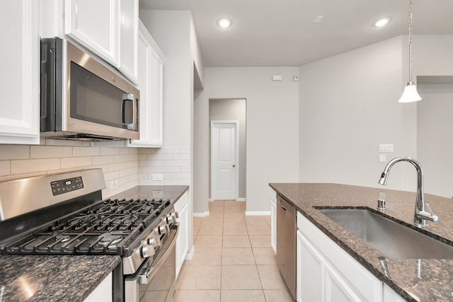 kitchen featuring dark stone counters, white cabinetry, appliances with stainless steel finishes, and decorative light fixtures