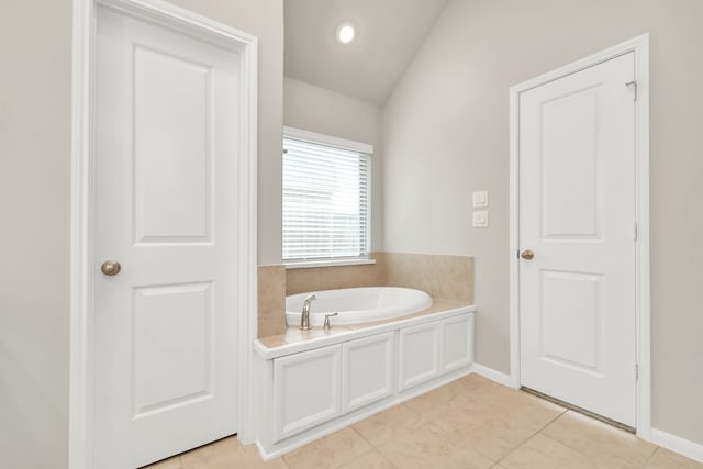 bathroom with a bathing tub, lofted ceiling, and tile patterned floors