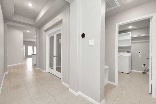 corridor featuring washer / clothes dryer and light tile patterned floors