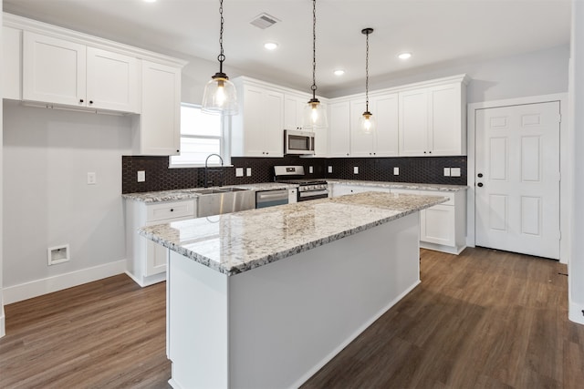 kitchen featuring stainless steel appliances, a kitchen island, decorative light fixtures, dark hardwood / wood-style floors, and white cabinets