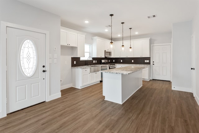 kitchen with white cabinets, pendant lighting, appliances with stainless steel finishes, and a center island