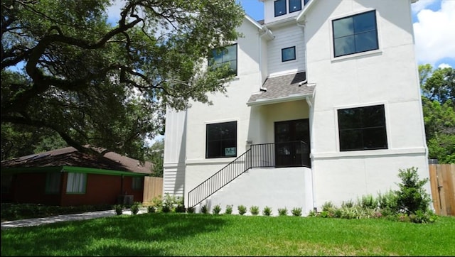 view of front of house with central air condition unit and a front lawn