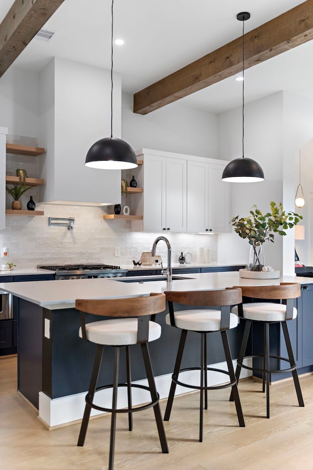 kitchen with sink, decorative light fixtures, beamed ceiling, and white cabinets