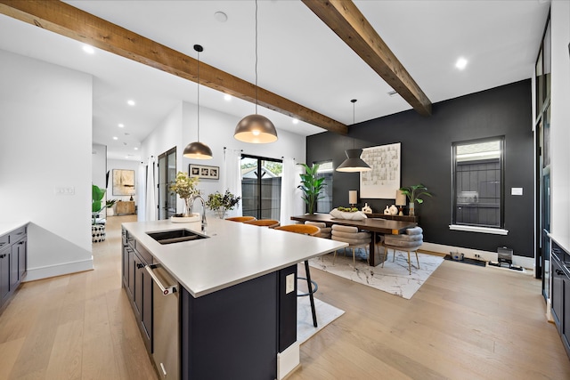 kitchen with sink, light hardwood / wood-style flooring, an island with sink, decorative light fixtures, and beamed ceiling