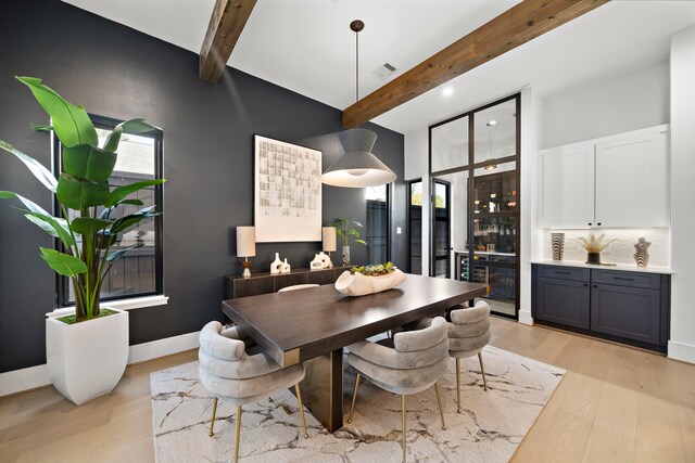 dining area with beamed ceiling and light wood-type flooring