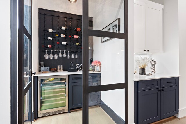 bar with white cabinetry, gray cabinetry, wine cooler, and light wood-type flooring