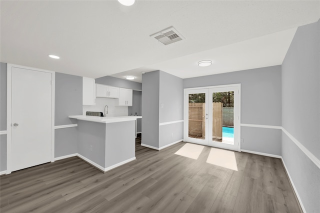 interior space featuring french doors, dark wood-type flooring, kitchen peninsula, a breakfast bar, and white cabinetry