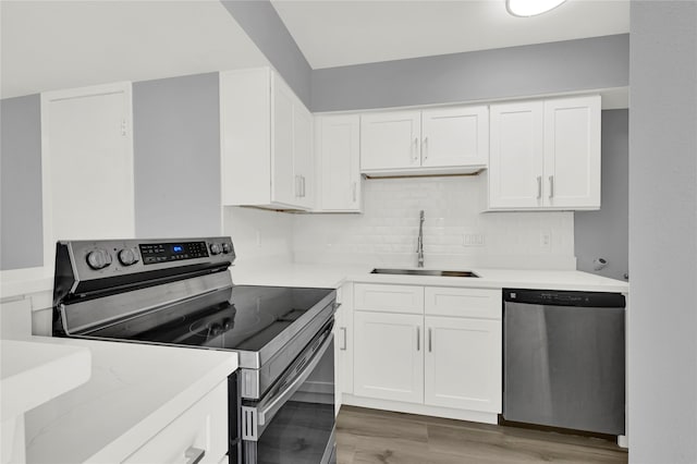 kitchen featuring white cabinets, stainless steel appliances, wood-type flooring, and sink