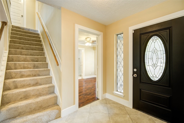 foyer with ceiling fan, a textured ceiling, and light hardwood / wood-style flooring