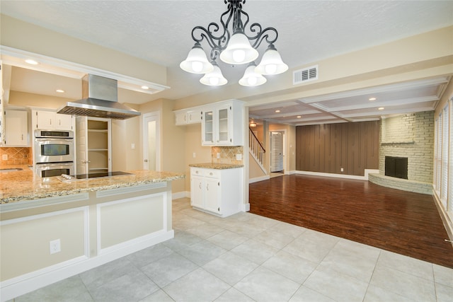 kitchen featuring white cabinets, light hardwood / wood-style floors, island range hood, and appliances with stainless steel finishes