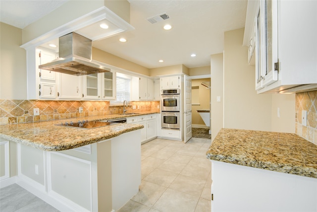 kitchen featuring stainless steel appliances, light stone counters, sink, island exhaust hood, and white cabinetry