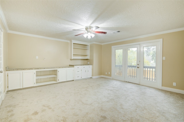 interior space with ceiling fan, a textured ceiling, french doors, and ornamental molding