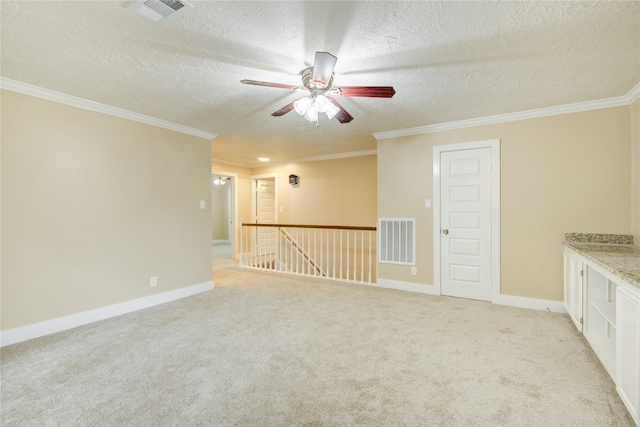 carpeted spare room featuring a textured ceiling, ceiling fan, and crown molding