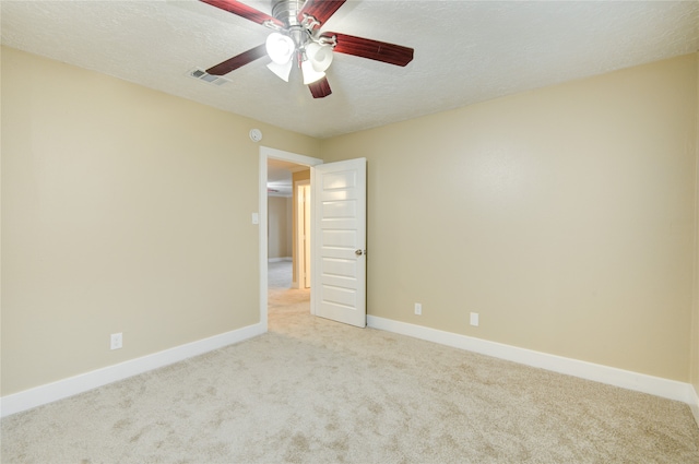 spare room with a textured ceiling, light carpet, and ceiling fan