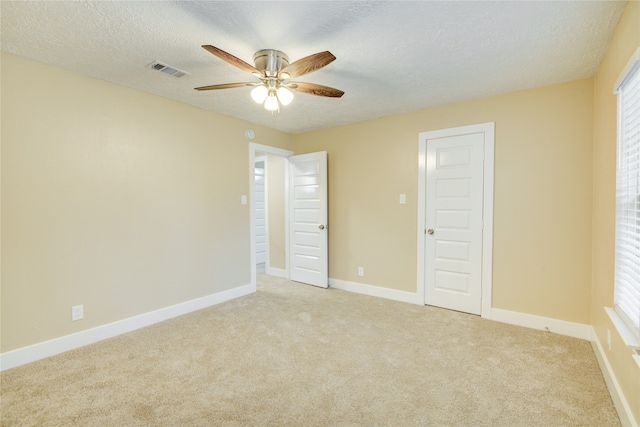 spare room with ceiling fan, light colored carpet, and a textured ceiling