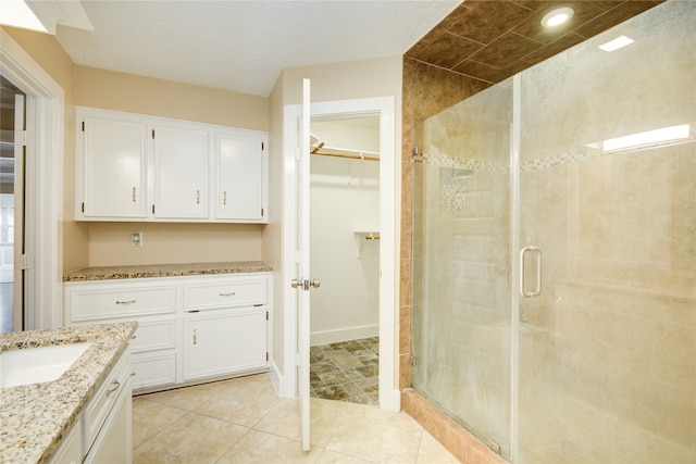 bathroom with a shower with door, vanity, and tile patterned flooring