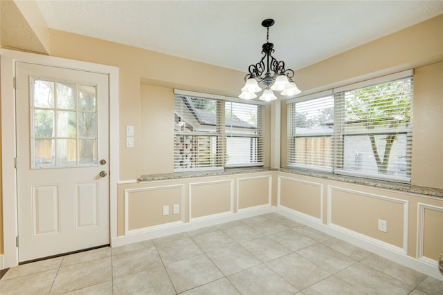 unfurnished dining area with an inviting chandelier and light tile patterned floors