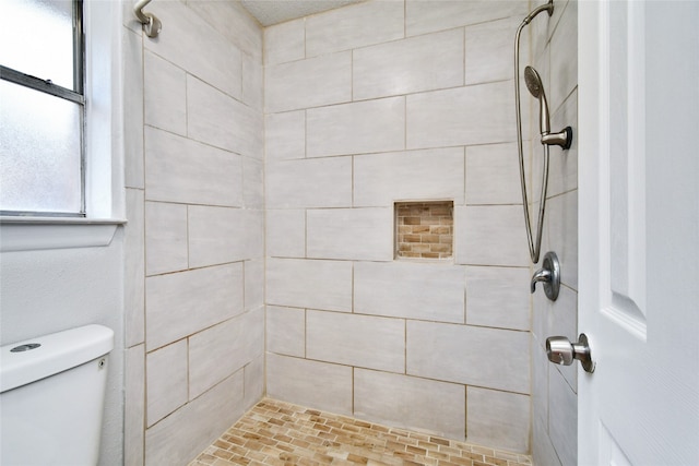 bathroom featuring toilet and a tile shower