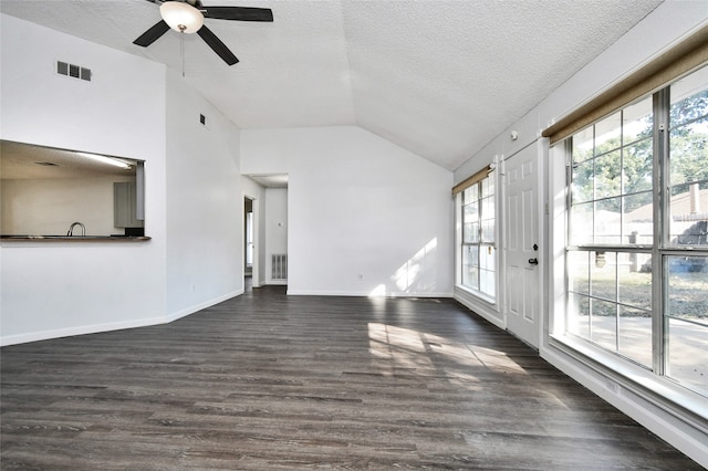 unfurnished living room featuring dark wood-type flooring, ceiling fan, a textured ceiling, and vaulted ceiling