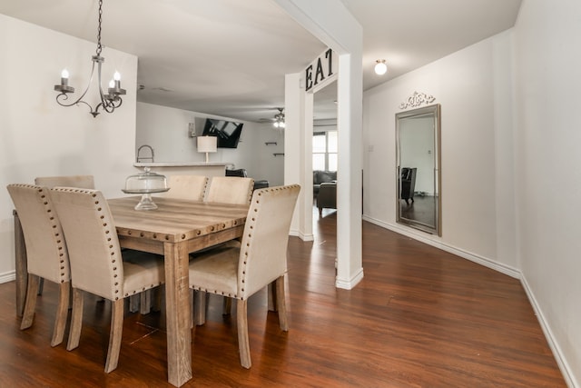 dining area with ceiling fan with notable chandelier and dark hardwood / wood-style flooring