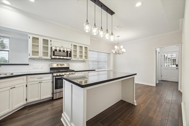 kitchen with stainless steel appliances, dark hardwood / wood-style flooring, a center island, white cabinetry, and decorative light fixtures