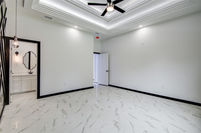 empty room with ornamental molding, ceiling fan, and a raised ceiling