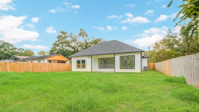 back of house with central air condition unit and a yard