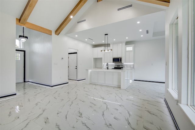 kitchen featuring white cabinetry, stainless steel appliances, a center island, and beam ceiling