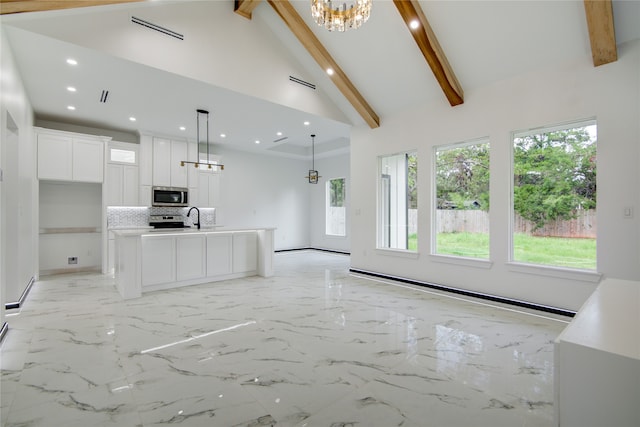 kitchen featuring stainless steel appliances, high vaulted ceiling, hanging light fixtures, white cabinets, and a kitchen island with sink