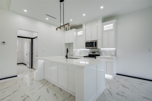 kitchen featuring stainless steel appliances, hanging light fixtures, white cabinetry, and an island with sink