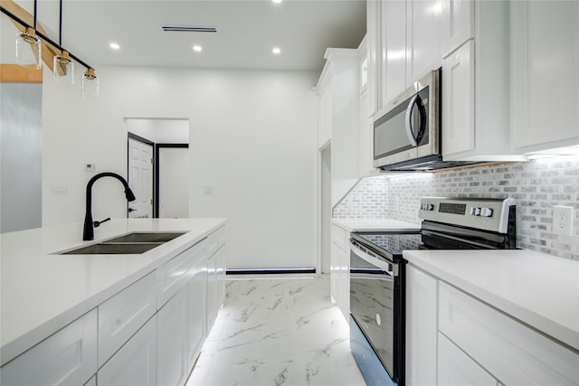 kitchen featuring stainless steel appliances, sink, backsplash, white cabinetry, and decorative light fixtures