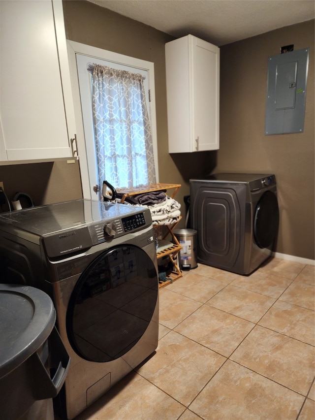 clothes washing area featuring cabinets, light tile patterned flooring, electric panel, and washer and clothes dryer